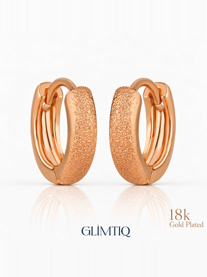 Close view of everyday gleam 18k rose gold plated huggie earrings showing textured, stone-free compact hoop