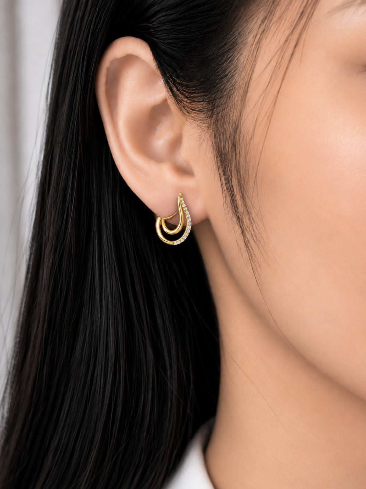 Golden Swoop 18K Gold Plated Huggie Earrings worn on a model's ear