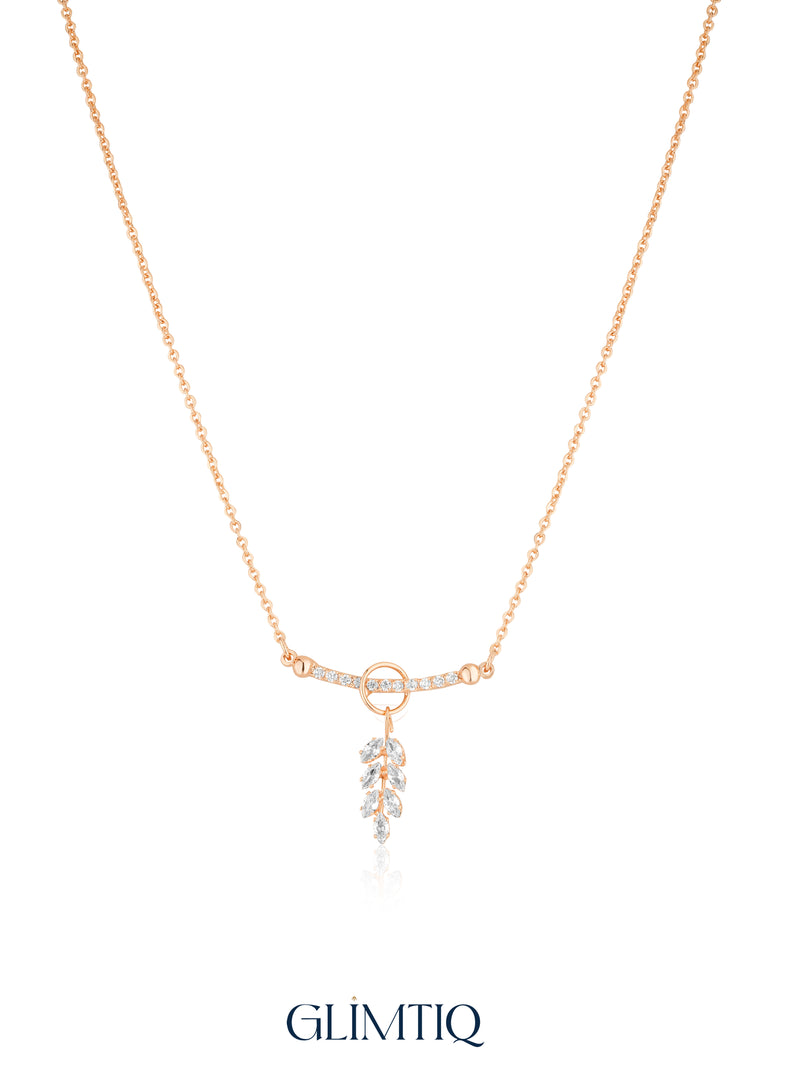 Gold necklace studio view with open circle, sparkling curved bar and hanging leaf drop