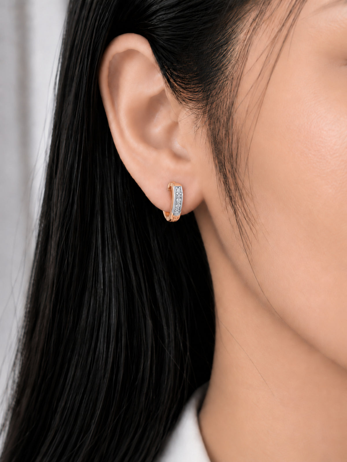 Two Tone Curve 18K Rose Gold Plated Hoops worn on a model's ear