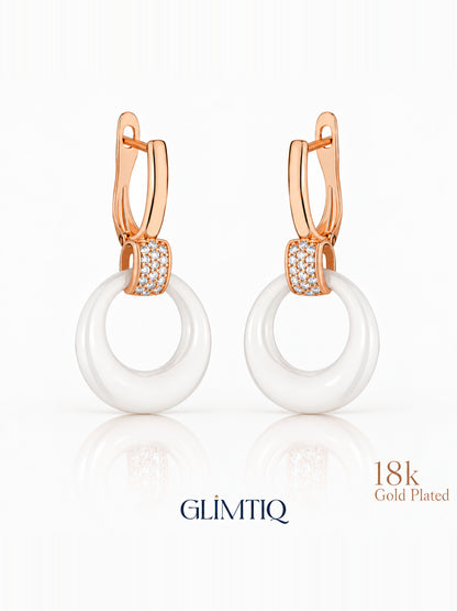 Close view of white halo 18k rose gold plated drop earrings showing white circular drop with a sparkling connector